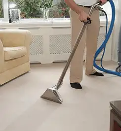 Professional carpet cleaner using a hot-water extraction wand and hose machine in a living room in Orlando, FL.