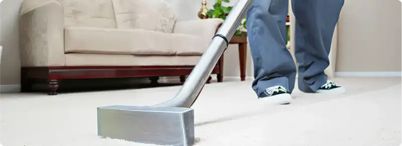 Carpet cleaning technician using a hot-water extraction wand on a light-colored carpet in a living room, Orlando, FL.