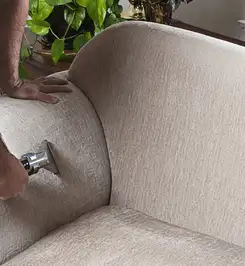 Professional upholstery cleaner deep-cleaning a fabric sofa with a handheld extraction tool and hose Orlando, FL.